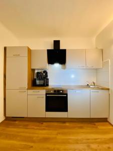 a kitchen with white cabinets and a stove top oven at Siriuskogel im Zentrum von Bad Ischl in Bad Ischl