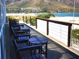 a balcony with tables and chairs and a view of the beach at Dune Lodge in Hout Bay