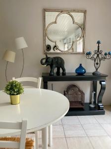 een eetkamer met een witte tafel en een spiegel bij Le Clos Nicolas in Eugénie-les-Bains