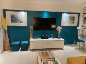 a living room with a tv and a blue wall at Appartement de standing Le Velvet Bay climatisé en bord de mer in Antibes
