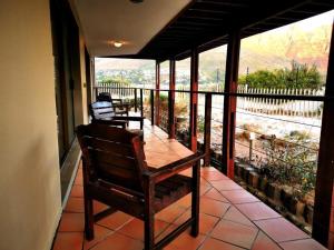 a porch with a wooden chair on a balcony at Dune Lodge in Hout Bay