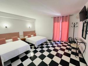 Micaela Charming Hostal في توريمولينوس: غرفة بسريرين وارضية مضلمة