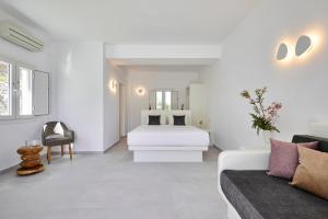 a white bedroom with a bed and a couch at Anchor Suites in Oia