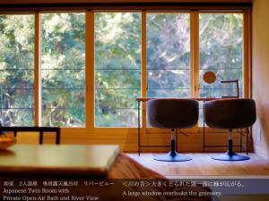 a room with a table and two chairs in front of a window at Tatsuta Ryokan in Izu