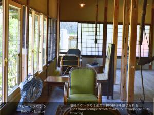 a room with chairs and tables and windows at Tatsuta Ryokan in Izu