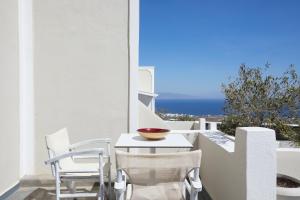 uma mesa e cadeiras numa varanda com vista para o oceano em Anchor Suites em Oia