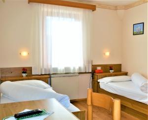 una camera con due letti e un tavolo e una finestra di Hotel Stella Alpina a Bellamonte