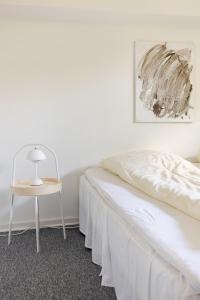 - une chambre blanche avec un lit blanc et une chaise dans l'établissement Værelse i rolig villakvarter, central beliggenhed, à Odense