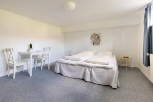 een witte slaapkamer met een bed en een tafel bij Værelse i rolig villakvarter, central beliggenhed in Odense