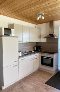 Il comprend une cuisine avec des placards blancs et un plafond en bois. dans l'établissement Altefähr, à Altefähr