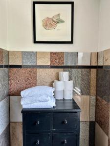 a black cabinet with towels and a picture on the wall at Anne Just's Havehotel in Blokhus