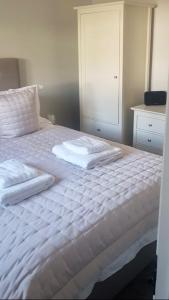 a white bed with two towels on top of it at Fern Cottage in Lynton