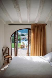 a bedroom with a bed and a chair and a window at Riurau de Maria in Parcent
