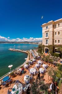 a beach with tables and chairs next to a building at Appartement de standing Le Velvet Bay climatisé en bord de mer in Antibes
