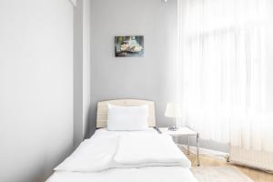 a white bedroom with a bed and a table at Modern Stylish Cozy Flat in the Heart of Kadikoy in Istanbul