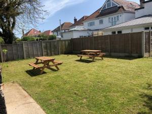 two picnic tables in a yard next to a fence at New 2 bedroom first floor apartment close to beach in Southbourne