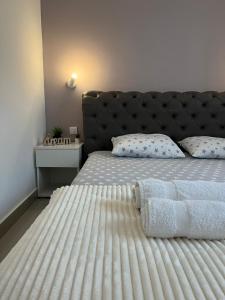 - une chambre avec un grand lit blanc et une tête de lit noire dans l'établissement Apartman Mijailović 3, à Sokobanja