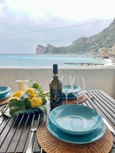 a table with plates and a bottle of wine and glasses at La Marina - Casa al Mare in Nerano