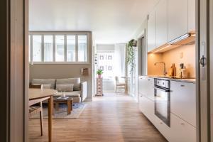 een keuken en een woonkamer met een tafel en een bank bij Scandinavian apartment with 2 bedrooms and terrasse - close to Storo Storsenter and all public transport in Oslo