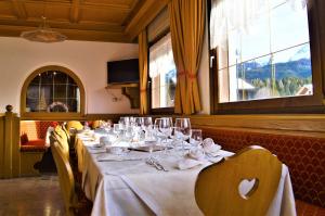 a dining room with a long table with wine glasses at Hotel Stella Alpina in Bellamonte