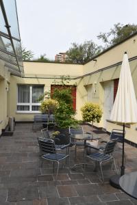 eine Terrasse mit Stühlen, einem Tisch und einem weißen Sonnenschirm in der Unterkunft Hotel du Commerce in Basel