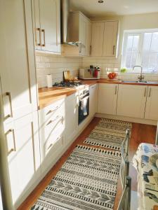 una cocina con armarios blancos y una alfombra en el suelo en Cosy Family Home in Long Eaton, Nottingham en Nottingham