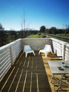 2 weiße Stühle und ein Tisch auf einer Terrasse in der Unterkunft Activités Et Nature Appartement in Vignot