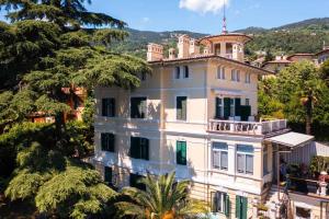 a large white house with a balcony on top of it at Apartmani Belsito in Lovran