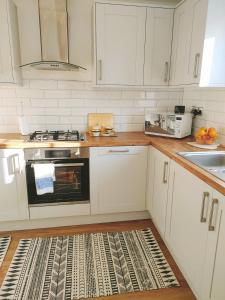 een keuken met witte kasten en een fornuis met oven bij Cosy Family Home in Long Eaton, Nottingham in Nottingham