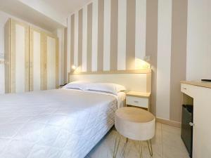 1 dormitorio con cama blanca y taburete en Aura Living Hotel, en Rímini