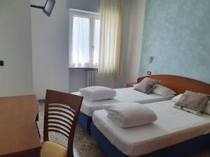 a bedroom with two beds and a desk and a table at Hotel 2 Palme in Torri del Benaco