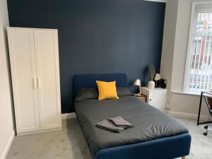 ein blaues Schlafzimmer mit einem Bett und einem gelben Kissen in der Unterkunft Ayresome House in Middlesbrough