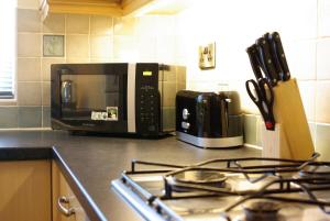 a kitchen counter with a stove and a microwave at Portland Mews - 3 Bed Holiday Home By Premier Serviced Accommodation in Leek