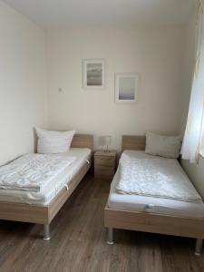 two beds in a room with white walls and wooden floors at Störtebeker 9 in Gnies