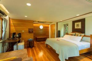 um quarto com uma grande cama branca e uma secretária em Kaengkrachan Boathouse Paradise Resort em Kaeng Kachan