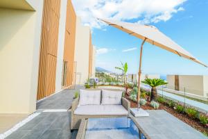 a patio with a white couch and an umbrella at Green Cost Luxury Apt 239 in Palasë