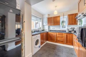 a kitchen with wooden cabinets and a washer and dryer at COSY HOME NEAR DORNEY, WINDSOR & Free Parking in Taplow