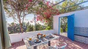 une table et des chaises sur une terrasse avec une grande fenêtre dans l'établissement Casa Andalucía Vélez-Málaga by Ruralidays, à Vélez-Málaga