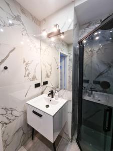 uma casa de banho branca com um lavatório e um chuveiro em Kamienica Łódzka em Lódź