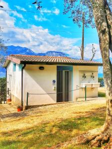 een klein wit huis met een boom ervoor bij Camping Baldo in Brenzone sul Garda