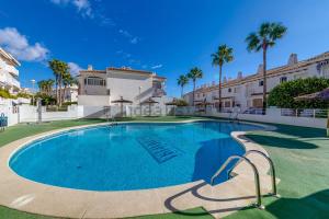 a swimming pool in front of a building with palm trees at Aguamarina Playa in Orihuela