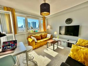 a living room with a yellow couch and a television at GOLD 2 King Size Bed, metro x2 free WiFi, 50'TV Netflix, HBO, AppleTV+ in Warsaw