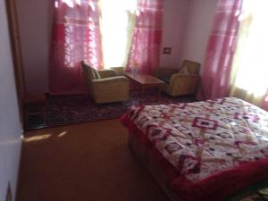 a bedroom with a bed and chairs and curtains at OYO Grand Inayat in Jawāharnagar