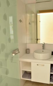 a white bathroom with a sink and a mirror at Anemoni Beach Hotel in Skiathos