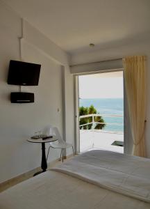 a bedroom with a bed and a view of the ocean at Anemoni Beach Hotel in Skiathos Town