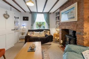 een woonkamer met een bank en een open haard bij Pip's Cottage by Staytor Accommodation in Exeter