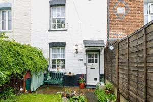 a small backyard with a green bench and a white house at Pip's Cottage by Staytor Accommodation in Exeter
