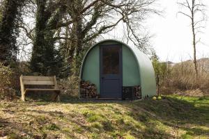 a small green dome house with a bench and a door at MotoCamp Wales in Dolgellau