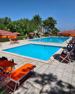 a large swimming pool with chairs and umbrellas at Il Grecale - Piscina e Ombrellone spiaggia prima fila incluso in Marcelli