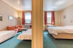 una habitación de hotel con 2 camas y una silla en Hôtel Le Cor de Chasse en Saint-Hubert